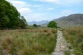 A rocky path on the right hand side of image leads across grassland to mountains in Snowdonia Royalty Free Stock Photo