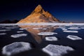 Rocky peak reflected in a frozen lake at night in the desert