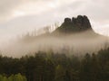 Rocky peak is sticking out from forest to dark grey cloud. Misty spring morning Royalty Free Stock Photo