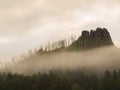 Rocky peak is sticking out from forest to dark grey cloud. Misty spring morning Royalty Free Stock Photo