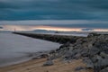 Rocky pier and threatening dark clouds during sunset at the beach Royalty Free Stock Photo