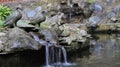 A rocky pond with a mini waterfall with some animal statues