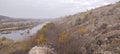 Rocky river bank among hills overgrown with vegetation, granite stones among dry yellowed grass. Royalty Free Stock Photo