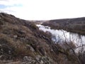 Rocky river bank among hills overgrown with vegetation, granite stones among dry yellowed grass Royalty Free Stock Photo