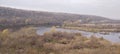 Rocky river bank among hills overgrown with vegetation, granite stones among dry yellowed grass Royalty Free Stock Photo