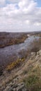 Rocky river bank among hills overgrown with vegetation, granite stones among dry yellowed grass Royalty Free Stock Photo