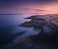 Rocky sea coast and lighthouse at colorful sunset in summer Royalty Free Stock Photo