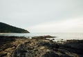 Rocky sea shore against a cloudy sky. Green hill on background cloudy sky Royalty Free Stock Photo