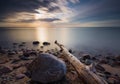 Rocky sea shore with driftwood at sunrise. Beautiful seascape Royalty Free Stock Photo