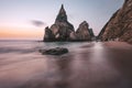 Rocky sea stacks at Portugal Ursa Beach at Atlantic Ocean coast in sunset light. Foamy waves rolling on picturesque Royalty Free Stock Photo