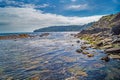 The shallow seaweed sea laps at the rocky Dorset shore