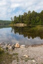 Rocky shore with Evergreen trees by a calm lake Royalty Free Stock Photo