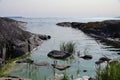 Rocky shore of lake Ladoga. Out of the water are the rocks and plants. There are many Islands on the horizon. Clear sunny day.