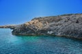 Rocky shore with large stones, turquoise and blue clear water. Transparent clear blue sky Royalty Free Stock Photo