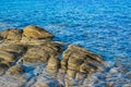 Rocky shore line scenic view waterfront blue water with evening orange lighting on stones