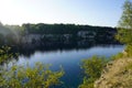 Rocky shore stone quarry with grass and shrubs. water is dark blue with reflection of stones. lake after the development of the