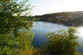 Rocky shore stone quarry with grass and shrubs. water is dark blue with reflection of stones. lake after the development of the