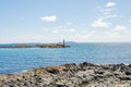 Rocky shoreline at Inishbofin or White Cow Island with the lighthouse on Gun Rock, with Inis Goirt in the background