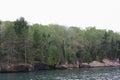 The rocky shoreline of Lake Superior lined with a variety of trees in a dense forest in Bayfield, Wisconsin Royalty Free Stock Photo