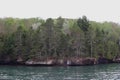 The rocky shoreline of Lake Superior lined with a variety of trees in a dense forest in Bayfield, Wisconsin, USA Royalty Free Stock Photo