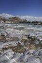 A rocky shoreline, with a white lighthouse on a headland. The beach is Bracelet Bay, Mumbles, south Wales Royalty Free Stock Photo