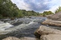 Rocky shores, rapids, fast river flow, bright green vegetation and a cloudy blue sky in summer Royalty Free Stock Photo