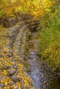 Rocky stream bank with mesh wire and golden leaves Royalty Free Stock Photo