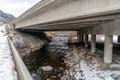 Rocky stream with shallow water and two lane road under an overpass highway Royalty Free Stock Photo