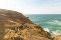 Rocky terrain. Ocean. The water is azure-colored. Light white waves. Clear blue sky. Light clouds. Yellow sand. Beautiful nature. Royalty Free Stock Photo