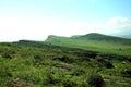 A rocky top of a high hill overlooking a fertile valley on a sunny summer day