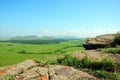 A rocky top of a high hill overlooking a fertile valley on a sunny summer day