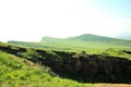 A rocky top of a high hill overlooking a fertile valley on a sunny summer day