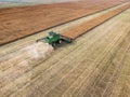 Aerial combine harvesting a wheat field with a dust trail on a hazy day on the
