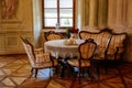 Rococo chateau interior, carved wooden furniture, armchairs and sofa, table set for tea, porcelain dishes, braided lace tablecloth