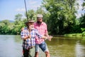 Rod tackle. Fishing equipment. Grandpa and mature man friends. Fishing with spinning reel. Sunny summer day at river Royalty Free Stock Photo