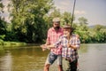 Rod tackle. Fishing equipment. Grandpa and mature man friends. Fishing with spinning reel. Sunny summer day at river Royalty Free Stock Photo