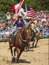 Rodeo. A man and a woman with the flags of Canada and America on horseback.