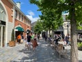 View on exterior shopping street with stores and people walking in summer