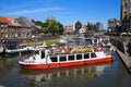 View on sightseeing cruise boat on dutch water canal with cityscape and church tower of old dutch town center against blue summer