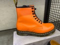 Closeup of one single orange color shoe in shelf of dr martens store