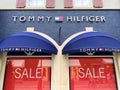 View on store facade with logo lettering of tommy hilfiger and red sale signs in window