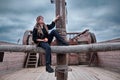 A rogue woman sits near the mast of an old pirate ship Royalty Free Stock Photo