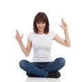 Rogue Young Woman Is Sitting On A Floor, Holding Arms Raised And Showing Pistol Hand Sign Royalty Free Stock Photo