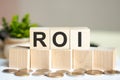 ROI concept with wooden blocks and coins on table, business concept. ROI - return on investment Royalty Free Stock Photo