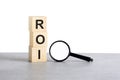 ROI - Return On Investment - text on wooden cube blocks and magnifying glass on grey table Royalty Free Stock Photo