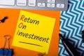 ROI Return On Investment written on dices in message at workplace background. Business performance indicator