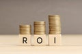 ROI word in wooden blocks with coins stacked in increasing stacks