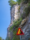 Roiling stones dangerous road. High cliffs and sign for falling rock pieces.