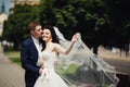 Roimantic newlyweds kiss on city alley. Blurred background