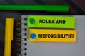 Roles and Responsibilities write on sticky notes isolated on Wooden Table Royalty Free Stock Photo